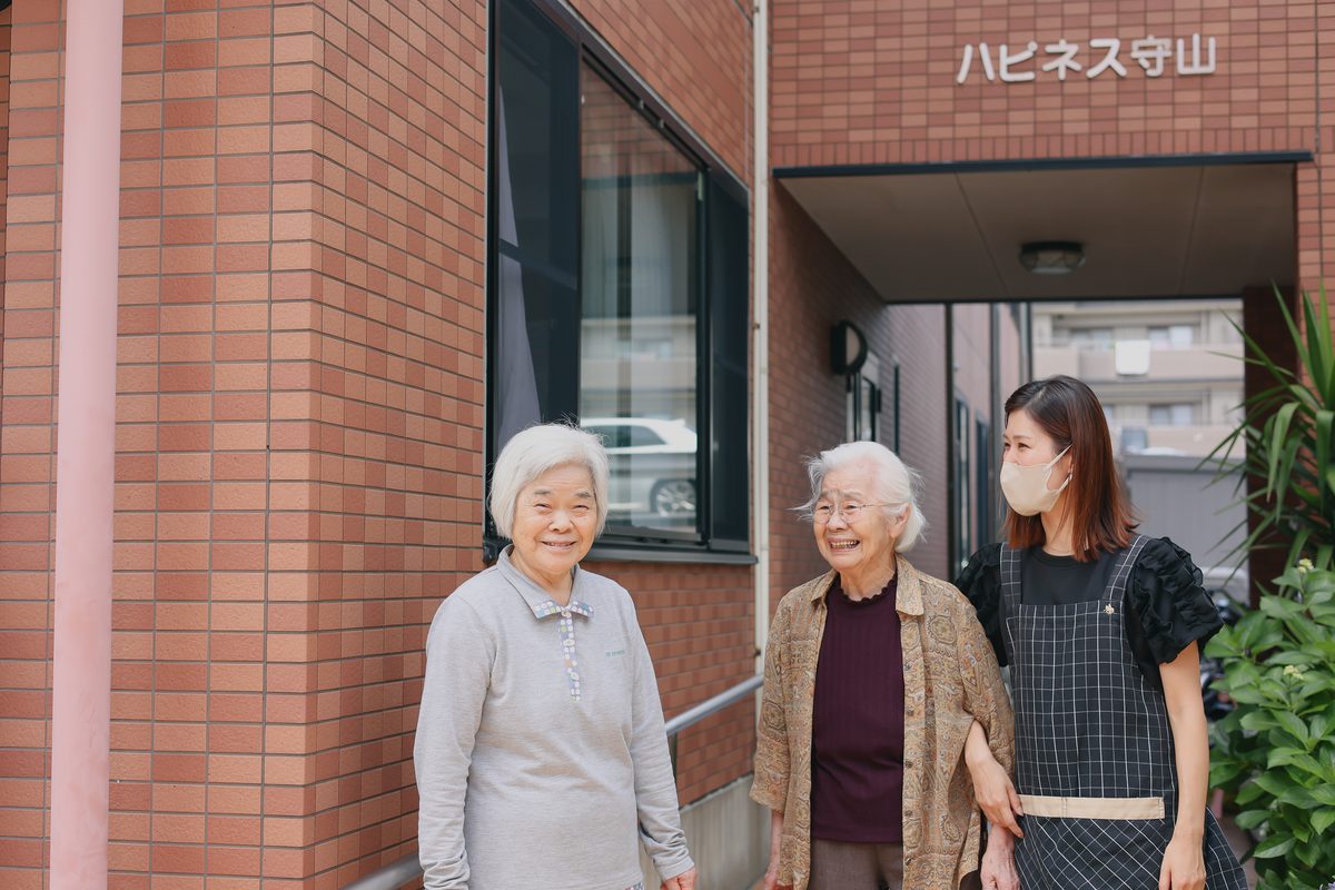 ハピネス守山 玄関前の入居者様とスタッフ